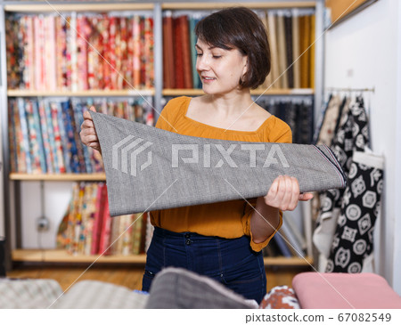 Happy woman choosing textiles 67082549
