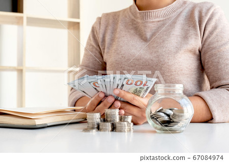Women are counting banknotes dollars on the table with coins saving money stepping into a growing business for success and taking notes 67084974