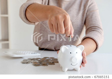 Women are putting coins in the piggy bank Saving money with coins Step into a business that is growing to be successful and save for retirement ideas 67085151