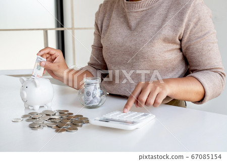 Women are putting dollar notes in a piggy bank with money-saving coins. Step into a growing business for success and save for retirement Women are putting dollar notes in a piggy bank with money-saving coins. Step into a growing business for success and save for retirement 67085154
