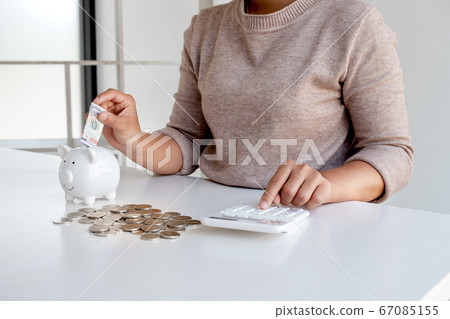 Women are putting dollar notes in a piggy bank with money-saving coins. Step into a growing business for success and save for retirement Women are putting dollar notes in a piggy bank with money-saving coins. Step into a growing business for success and save for retirement 67085155