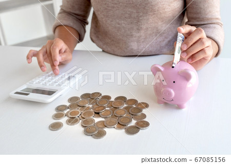 Women are putting dollar notes in a piggy bank with money-saving coins. Step into a growing business for success and save for retirement Women are putting dollar notes in a piggy bank with money-saving coins. Step into a growing business for success and save for retirement 67085156