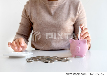 Women are putting dollar notes in a piggy bank with money-saving coins. Step into a growing business for success and save for retirement Women are putting dollar notes in a piggy bank with money-saving coins. Step into a growing business for success and save for retirement 67085157