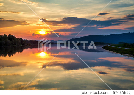 Mirroring of landscape at sunset on water surface Mirroring of landscape at sunset on water surface 67085692