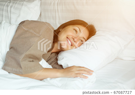 happy woman sleeps in bed with blanket and pillows in hotel happy woman sleeps in bed with blanket and pillows in hotel 67087727