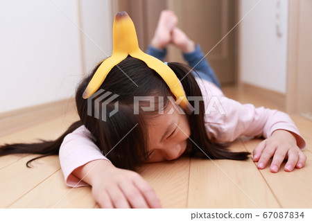 A girl who fell down on the banana skin that fell on the floor A girl who fell down on the banana skin that fell on the floor 67087834