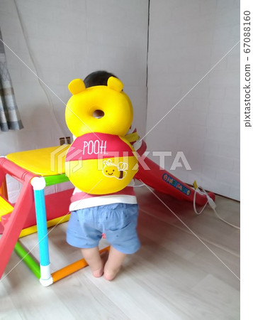 A baby playing with indoor play equipment with a head guard 67088160