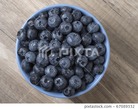 Bowl full of fresh ripe blueberries on a wooden 67089332