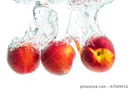 Nectarine fruits splashing into water and sinking Nectarine fruits splashing into water and sinking 67089418
