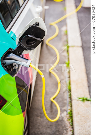 Modern electric cars EV Car plugged into charging 67089424