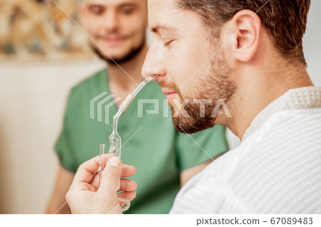 Man receives nasal inhalation. Man receives nasal inhalation. 67089483