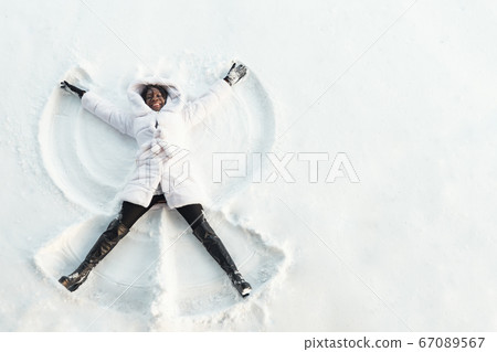 black girl lies on white forest glade and makes snow angles black girl lies on white forest glade and makes snow angles 67089567