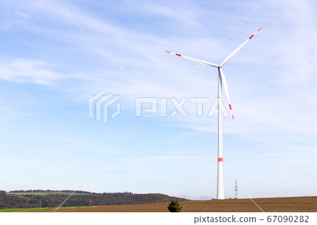 A windmill on a field with blue sky 67090282