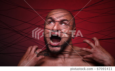 Portrait of tangled in threads bald screaming man 67091411