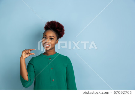 African-american beautiful young woman's portrait on blue studio background, emotional and expressive. Copyspace for ad. 67092765
