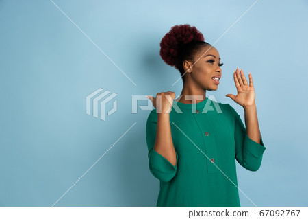 African-american beautiful young woman's portrait on blue studio background, emotional and expressive. Copyspace for ad. African-american beautiful young woman's portrait on blue studio background, emotional and expressive. Copyspace for ad. 67092767