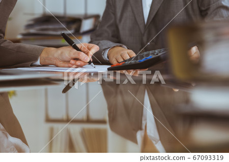 Two female accountants checking financial statement or counting by calculator income for tax form, hands close-up. Internal Revenue Service inspector checking financial document. Planning budget and Two female accountants checking financial statement or counting by calculator income for tax form, hands close-up. Internal Revenue Service inspector checking financial document. Planning budget and 67093319
