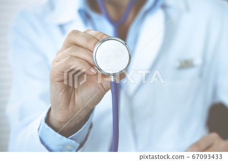 Unknown doctor woman holds stethoscope head, close-up. Physician ready to examine and help patient. Helping and insurance in health care, best treatment and medicine concept 67093433