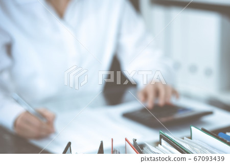 Binders of papers waiting to process by bookkeeper woman or financial inspector, close-up. Business portrait. Audit or tax concepts Binders of papers waiting to process by bookkeeper woman or financial inspector, close-up. Business portrait. Audit or tax concepts 67093439