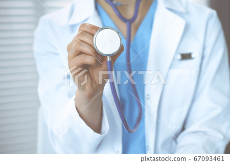 Unknown doctor woman holds stethoscope head, close-up. Physician ready to examine and help patient. Helping and insurance in health care, best treatment and medicine concept 67093461
