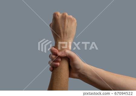 Close-up of light-skinned hand clenching dark-skinned wrist Close-up of light-skinned hand clenching dark-skinned wrist 67094522