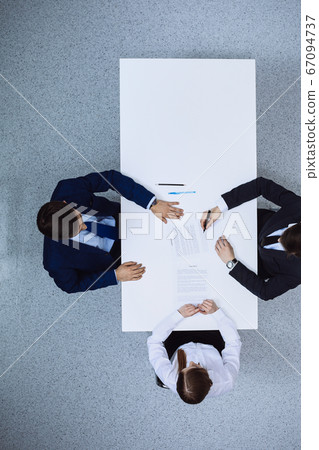 Group of business people and lawyer discussing contract papers sitting at the table, view from above. Businessman is signing document after agreement done 67094737