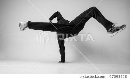 A man hip hop dancer or bboy freezes in one pose on a white background. Bboy doing stylish stunts. A man hip hop dancer or bboy freezes in one pose on a white background. Bboy doing stylish stunts. 67095328