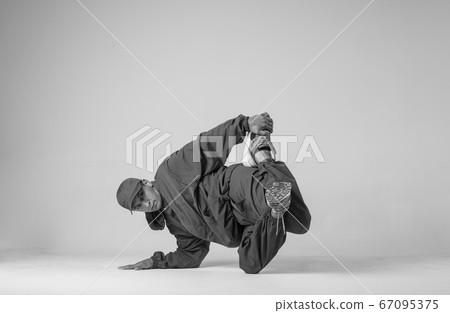 A man hip hop dancer or bboy freezes in one pose on a white background. Bboy doing stylish stunts. A man hip hop dancer or bboy freezes in one pose on a white background. Bboy doing stylish stunts. 67095375