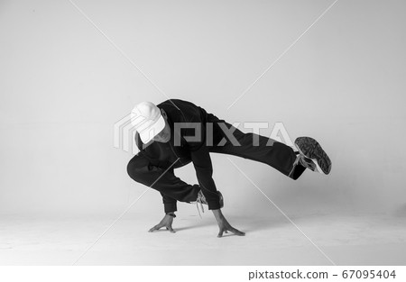 A man hip hop dancer or bboy freezes in one pose on a white background. Bboy doing stylish stunts. 67095404