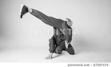 A man hip hop dancer or bboy freezes in one pose on a white background. Bboy doing stylish stunts. A man hip hop dancer or bboy freezes in one pose on a white background. Bboy doing stylish stunts. 67095434