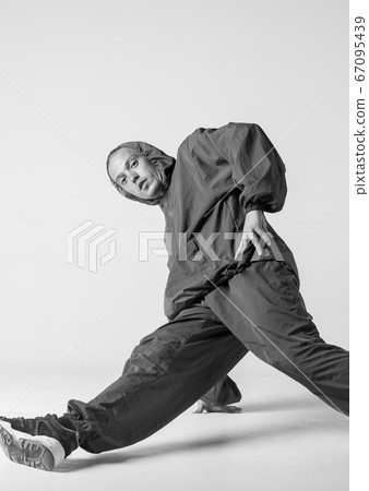 A man hip hop dancer or bboy freezes in one pose on a white background. Bboy doing stylish stunts. 67095439
