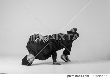 A man hip hop dancer or bboy freezes in one pose on a white background. Bboy doing stylish stunts. A man hip hop dancer or bboy freezes in one pose on a white background. Bboy doing stylish stunts. 67095453