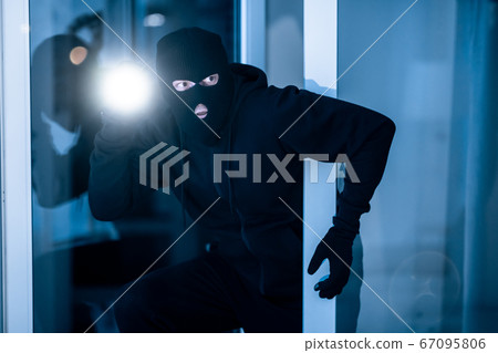 Thief breaking into apartment to steal, using torch 67095806