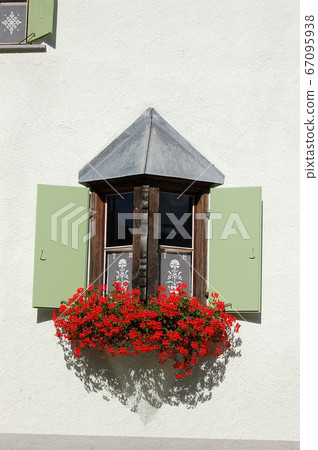 Balcony with windows and red geraniums - Zuoz village Engadine Switzerland 67095938