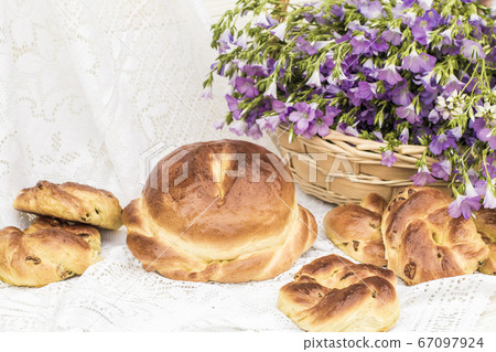 Delicious pastries (bread and rolls with raisins) and bouquet linen in wicker basket. Retro style, vintage 67097924
