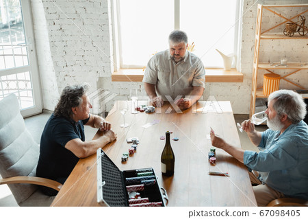 Group of happy mature friends playing cards and drinking wine Group of happy mature friends playing cards and drinking wine 67098405