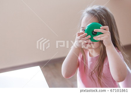 the child plays with a detail from the pyramid. the girl looks through the hole in the wheel. Concept of fine motor skills development, educational games, childhood, children's day, kindergarten, hous the child plays with a detail from the pyramid. the girl looks through the hole in the wheel. Concept of fine motor skills development, educational games, childhood, children's day, kindergarten, hous 67101861