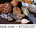 Concept of homemade bread, natural farm products, domestic production. Healthy and tasty organic food. Cut bread, milk, flour. Wheat spica as decor. Closeup, dark wooden background 67102107