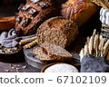 Concept of homemade bread, natural farm products, domestic production. Healthy and tasty organic food. Cut bread, milk, flour. Wheat spica as decor. Closeup, dark wooden background 67102109