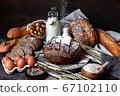 Concept of homemade bread, natural farm products, domestic production. Healthy and tasty organic food. Whole grain dark round bread, milk, eggs, flour, wheat spica. Closeup, dark wooden background 67102110