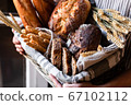 Concept of homemade bread, small bakery, natural farm products, domestic production. Healthy and tasty organic food. Woman holding basket with various bread freshly baked. Close up 67102112