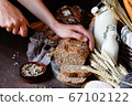 Concept of homemade bread, natural farm products, domestic production. Healthy and tasty organic food. Woman cutting freshly baked whole grain bread. Close up, dark black wooden background. 67102122