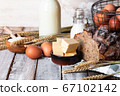 Concept of homemade bread, natural farm products, domestic production. Healthy and tasty organic food. Eggs, butter, bread, milk, flour. Wheat spica as decor. Closeup, wooden background 67102142