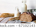 Concept of homemade bread, natural farm products, domestic production. Healthy and tasty organic food. Bread, milk, flour. Wheat spica as decor. Closeup, wooden background 67102143