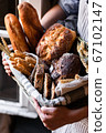 Concept of homemade bread, small bakery, natural farm products, domestic production. Healthy and tasty organic food. Woman holding basket with various bread freshly baked. Close up 67102147