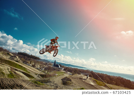 Extreme concept, challenge yourself. Extreme jump on a motorcycle on a background of blue sky with clouds. Copy space, all or nothing. 67103425