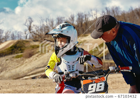 kids riding at motobike, junior competition on motorcycle. Coach gives instructions to his young rider kids riding at motobike, junior competition on motorcycle. Coach gives instructions to his young rider 67103432