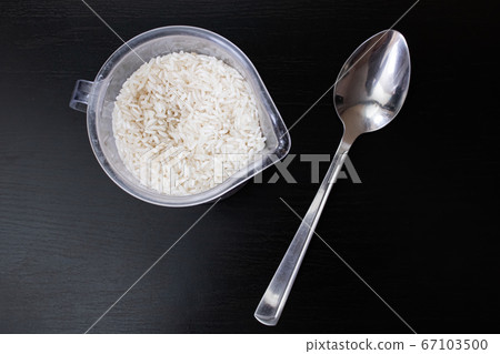 Rice grains and spoon on wooden background Rice grains and spoon on wooden background 67103500