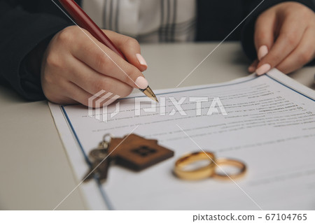 Hands of wife, husband signing decree of divorce, dissolution, canceling marriage, legal separation documents, filing divorce papers or premarital agreement prepared by lawyer. Wedding ring Hands of wife, husband signing decree of divorce, dissolution, canceling marriage, legal separation documents, filing divorce papers or premarital agreement prepared by lawyer. Wedding ring 67104765