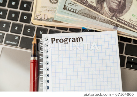Notepad with word program and money on the laptop. 67104800